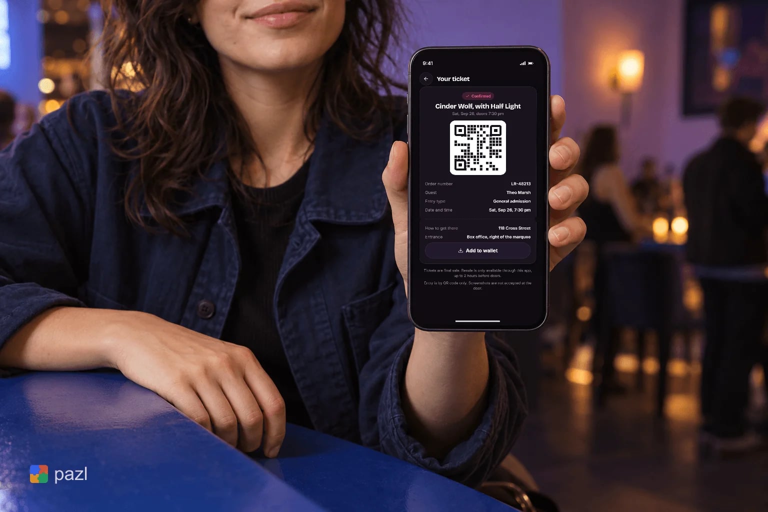 Eine Besucherin an einem Bartisch hält ein Smartphone mit einem Ticket und seinem QR-Code hoch